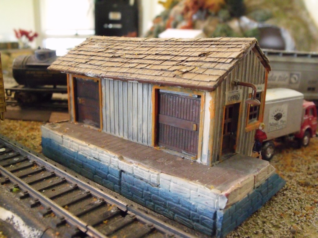 A Cheap Bachmann train set building with new paint, a new roof of construction paper shingles, and cinder-block loading dock made from an old kit.